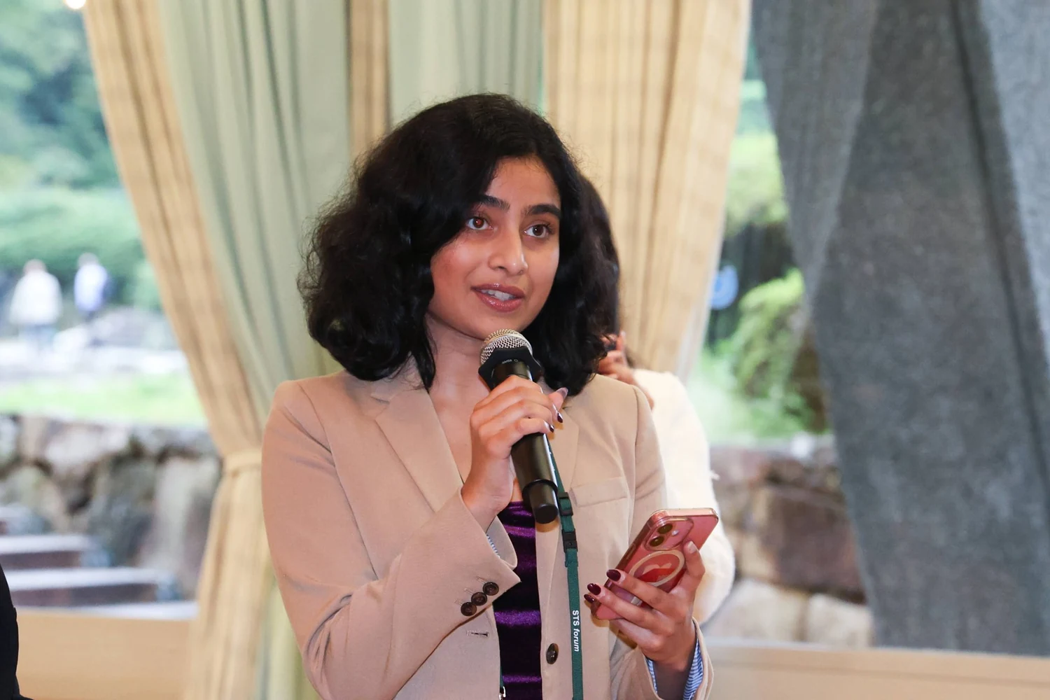 Ria Bahadur speaking with a microphone at the STS Forum