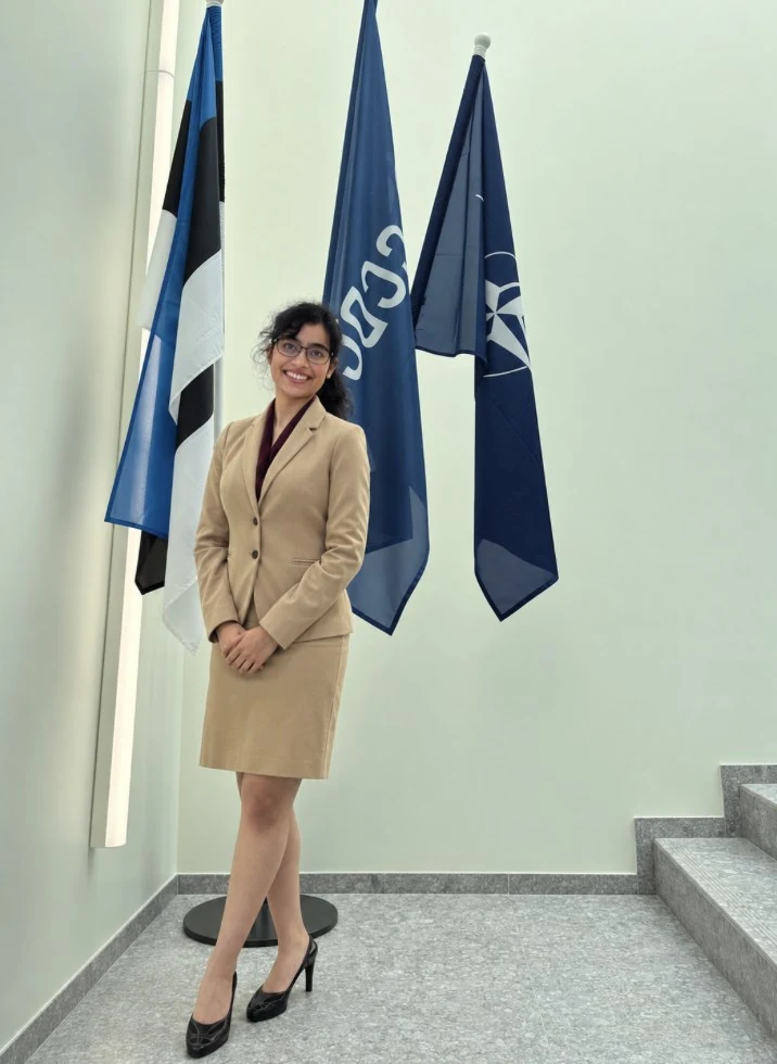 Ria Bahadur standing beside the flags at NATO CCDCOE in Tallinn